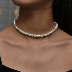 A close-up of a woman's neck wearing the Vintage Style Simple 6MM Pearl Chain Choker Necklace, styled with a black off-the-shoulder top that highlights this elegant shell pendant fashion jewelry for women.