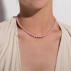 A woman wearing a light beige V-neck blouse models the Vintage Style Simple 6MM Pearl Chain Choker Necklace, shown from the shoulders up against a textured white wall, with her face partially out of frame.