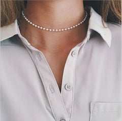 A close-up of a person in a white button-up shirt wearing the Vintage Style Simple 6MM Pearl Chain Choker Necklace for Women, featuring an elegant shell pendant and highlighting chic women’s fashion jewelry.