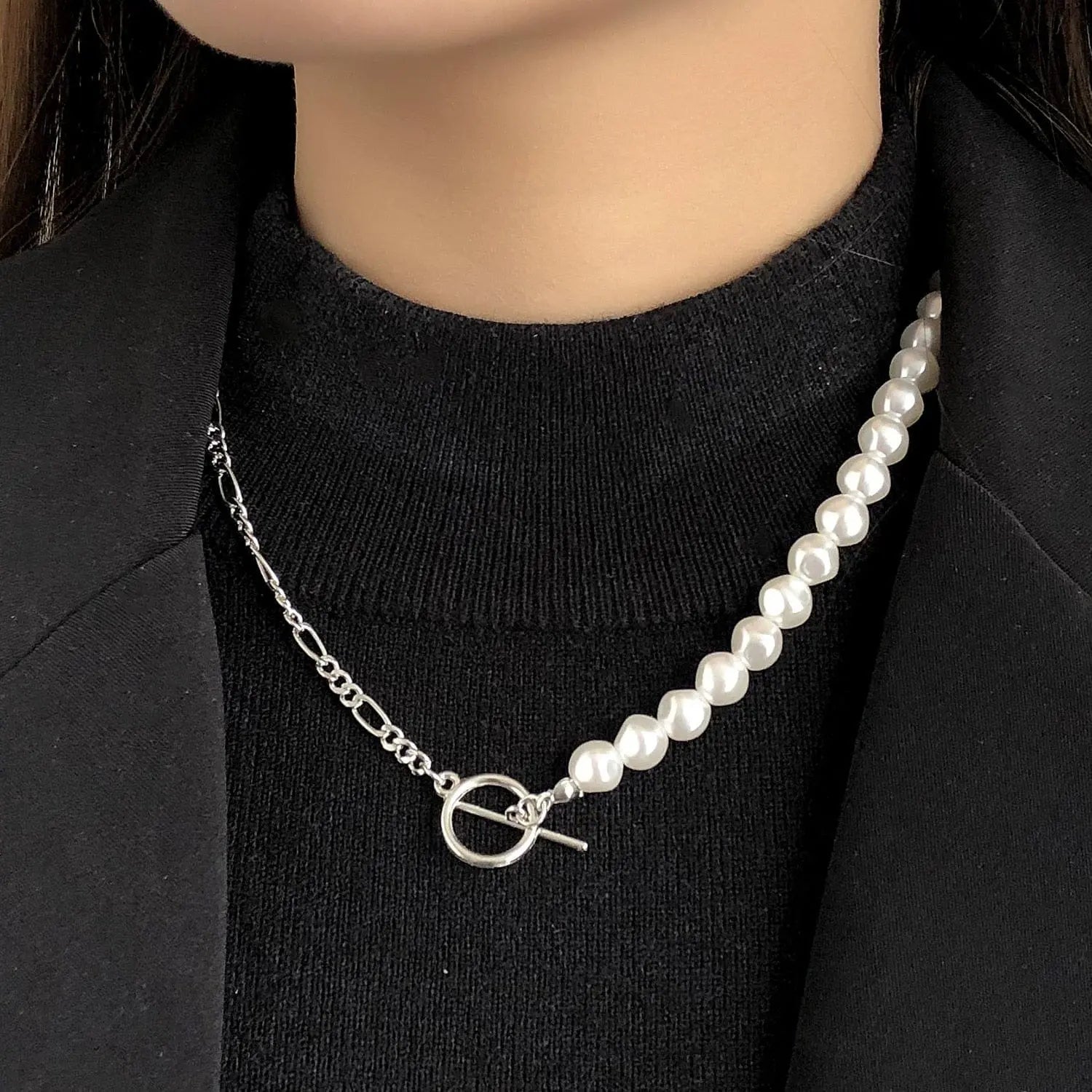 A close-up of a woman wearing the Vintage Style Simple 6MM Pearl Chain Choker Necklace, featuring white pearls and a silver chain with toggle clasp, styled over a black turtleneck and blazer.