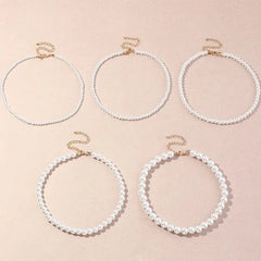 Five Vintage Style Simple 6MM Pearl Chain Choker Necklaces for women, each with gold clasps and assorted bead patterns, are displayed on a light pink surface.