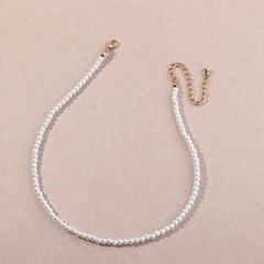 The Vintage Style Simple 6MM Pearl Chain Choker Necklace for women features elegant white pearls and a gold clasp, arranged in a graceful curve on a light beige background—perfect for weddings and fashion lovers.