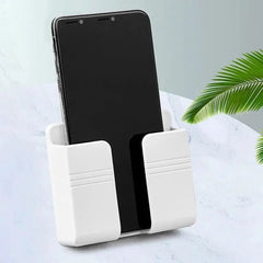 A white wall-mounted plastic holder containing a smartphone, set against a marble-patterned surface.
