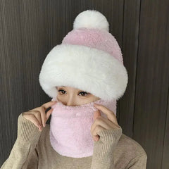 A woman wears a pink and white plush hooded scarf set with a fluffy pom-pom beanie.