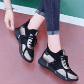 A pair of black and metallic gold lace-up sneakers worn with dark blue jeans.