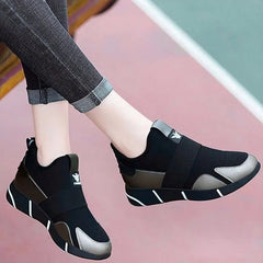 A pair of black slip-on sneakers with metallic silver accents and white striped soles.