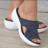 A pair of blue open-toe wedge sandals with a white platform sole worn on feet.