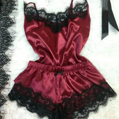 A burgundy satin pajama set featuring a sleeveless camisole and shorts with black lace trim.