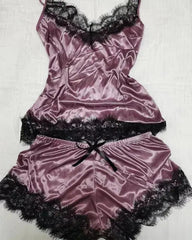 A mauve satin pajama set featuring a sleeveless camisole and shorts with black lace trim.