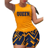 A woman wears a yellow sleeveless top with the word Queen and matching geometric print shorts.
