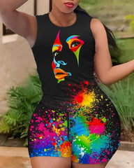 A woman wears a black sleeveless top and shorts set featuring a colorful abstract face and paint splatter print.