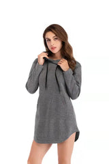 A woman wears a grey long-sleeved hooded sweatshirt dress with a front kangaroo pocket.