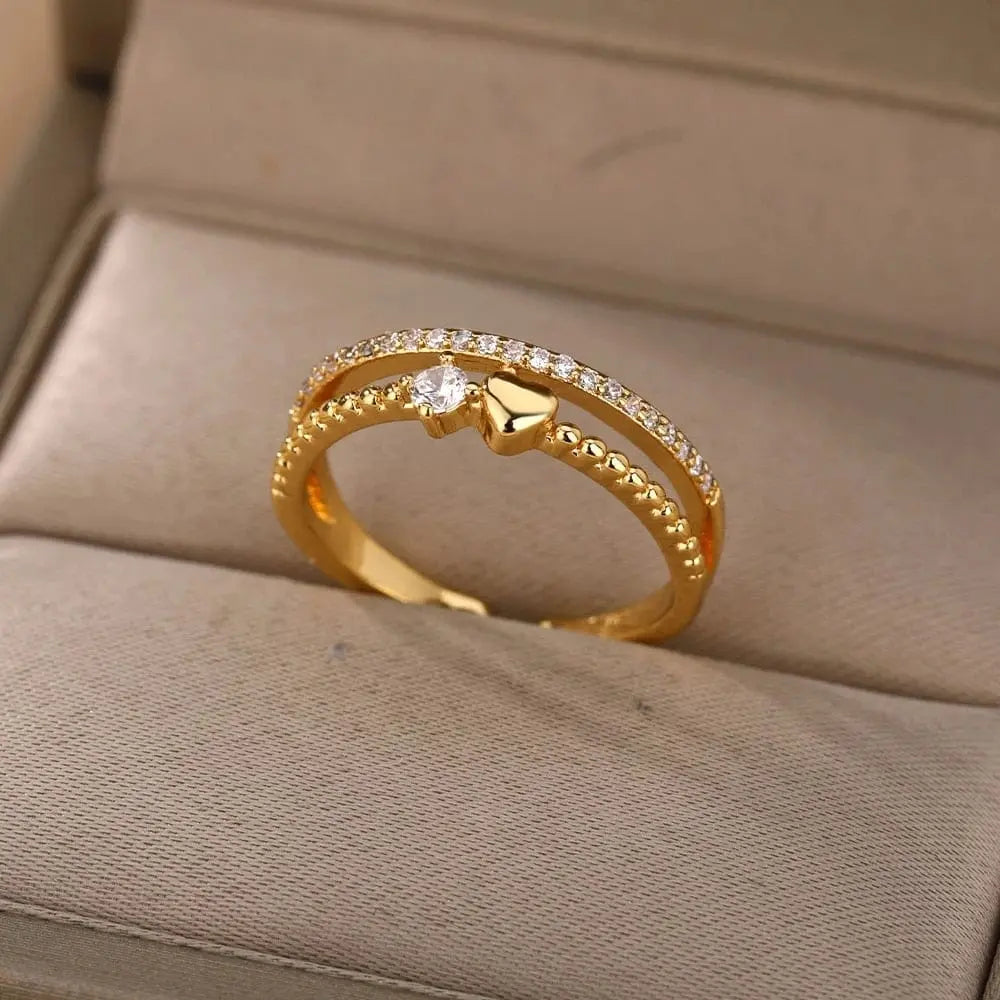 The Zircon Engagement Wedding Ring for Women features two gold bands—one with diamonds, the other with gold beads—joined by a heart and central cubic zirconia. This elegant stainless steel ring makes a perfect gift and comes with free shipping.