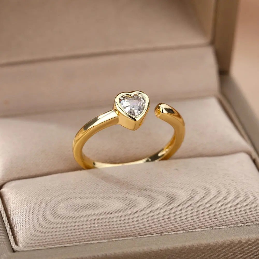 The Zircon Engagement Wedding Ring for women features a gold-colored stainless steel open band with a heart-shaped cubic zirconia, presented in a beige jewelry box—ideal as finger jewelry or a birthday gift, with free shipping.