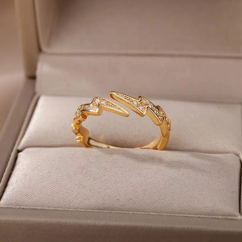A gold color stainless steel zircon engagement ring for women, designed with sparkling cubic zirconia, is displayed in an open beige jewelry box.