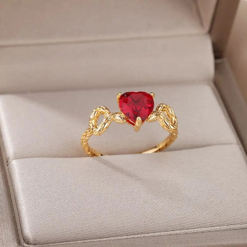 A gold color stainless steel ring for women with a heart-shaped red zircon, featuring a twisted band—an elegant 2023 zircon engagement or wedding ring, perfect as a birthday gift. Comes in a cushioned jewelry box with free shipping.