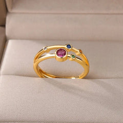 The Zircon Engagement Wedding Ring for women features a central pink gemstone with blue, green, orange, and clear Cubic Zirconia accents on gold-colored stainless steel, shown on a beige jewelry box. Ideal as a birthday gift with free shipping.