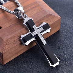 A stainless steel cross pendant necklace featuring a black inlay and a small cubic zirconia cross.