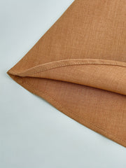 A close-up view of the hemline of a solid brown woven dress.