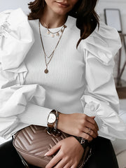 A woman wears a white ribbed long-sleeve blouse featuring dramatic puff sleeves and a crew neck.