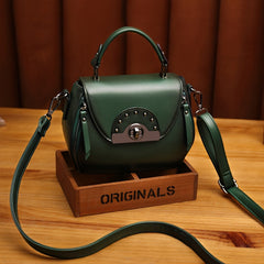A dark green apple-shaped crossbody bag with a top handle, metal clasp, and adjustable strap.
