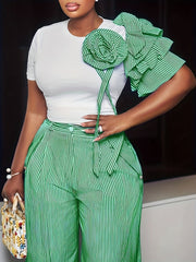 A woman wears a white crew neck top with a green striped ruffled sleeve and matching wide-leg pants.