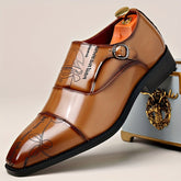 A tan leather monk strap shoe with a unique decorative pattern and a black sole.