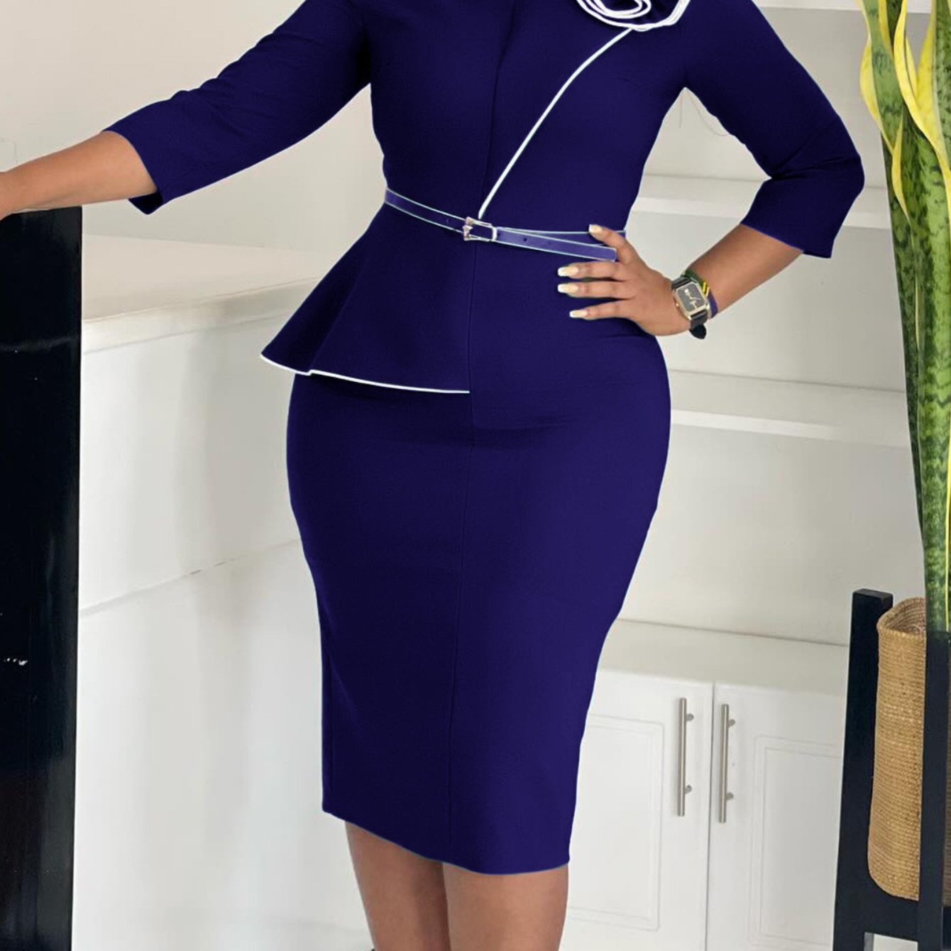 A dark blue knee-length pencil dress with a peplum waist, white trim, and a matching belt.