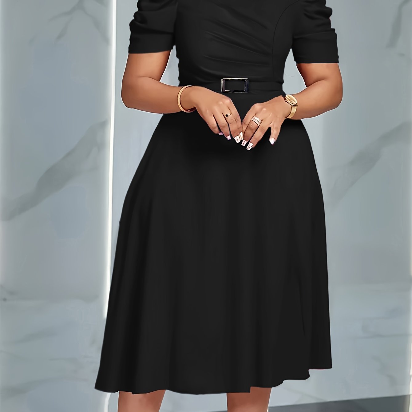 A woman wears a black short-sleeved A-line dress with a belted waist and a fitted bodice.
