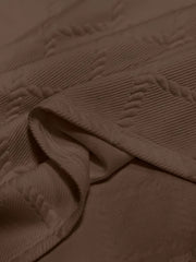 A close-up view of a brown men's t-shirt featuring a textured geometric jacquard knit pattern.
