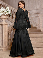A plus size black sequin lace gown with a V-neck, long bell sleeves, and a mermaid tulle hem.