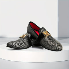 A pair of black and grey floral pattern loafers featuring a gold buckle and red interior lining.