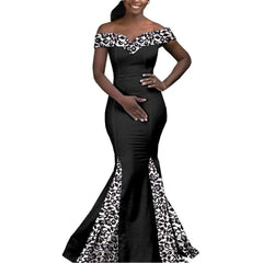 A woman wears a black off-the-shoulder floor-length mermaid dress with white floral lace accents.