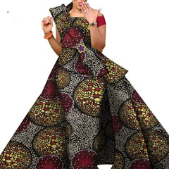 A woman wears a floor-length African print dress with a structured bodice and off-shoulder sleeves.