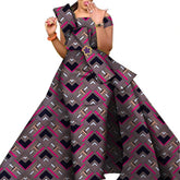 A woman wears an off-the-shoulder floor-length dress featuring a geometric black and pink print.