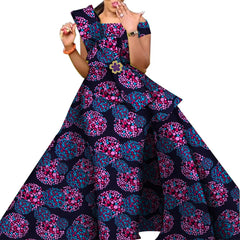 A woman wears a floor-length off-the-shoulder dress featuring a dark blue and pink polka dot print.