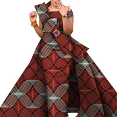 A woman wears a floor-length, off-the-shoulder African print dress with a decorative waist accent.