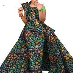 A woman wears a floor-length African print dress with a colorful geometric pattern.