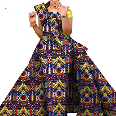 A woman wears a floor-length African print dress with a vibrant geometric pattern.