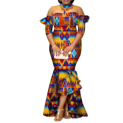 A woman wears a long, off-the-shoulder African print dress with a high-low ruffled hem.