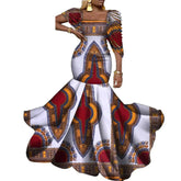 A woman wears a white floor-length dress featuring a vibrant red, yellow, and blue African print.