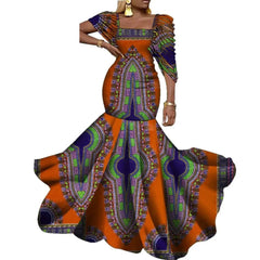 A woman wears an elegant orange and purple African wax print mermaid dress with a square neckline.