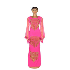 A floor-length hot pink mermaid dress with sheer flare sleeves and gold diamond embellishments.