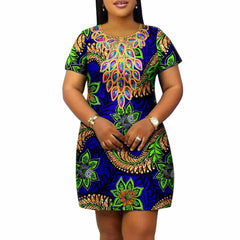 A woman wears a blue knee-length dress with a vibrant green and gold floral Ankara print.