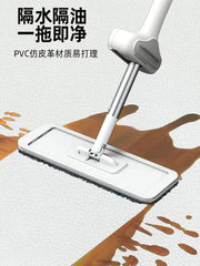 A white flat mop cleaning a spill on a patterned kitchen floor mat.