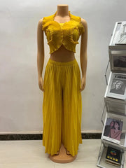 A bright yellow two-piece set featuring a ruffled halter crop top and pleated wide-leg pants.