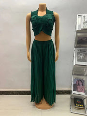 A dark green two-piece set featuring a sleeveless ruffled crop top and matching pleated wide-leg pants.