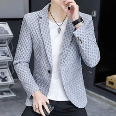 A man wears a slim-fit, light grey blazer with a textured, repeating geometric pattern.