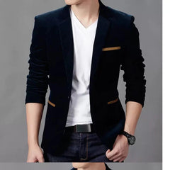 A man wears a slim-fit navy blue corduroy blazer with tan pocket accents over a white v-neck shirt.