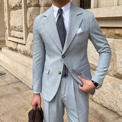 A man wears a light grey striped single-breasted suit jacket with a white shirt and dark tie.